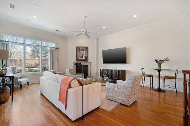 living room featuring ceiling fan, crown molding, and wood-type flooring