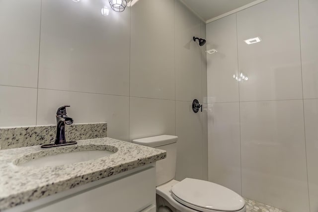 bathroom featuring vanity, toilet, tile walls, and a shower