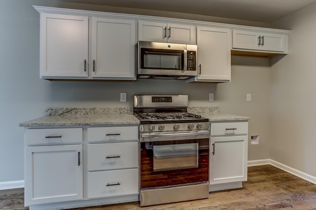 kitchen featuring light stone countertops, white cabinetry, appliances with stainless steel finishes, and light hardwood / wood-style floors