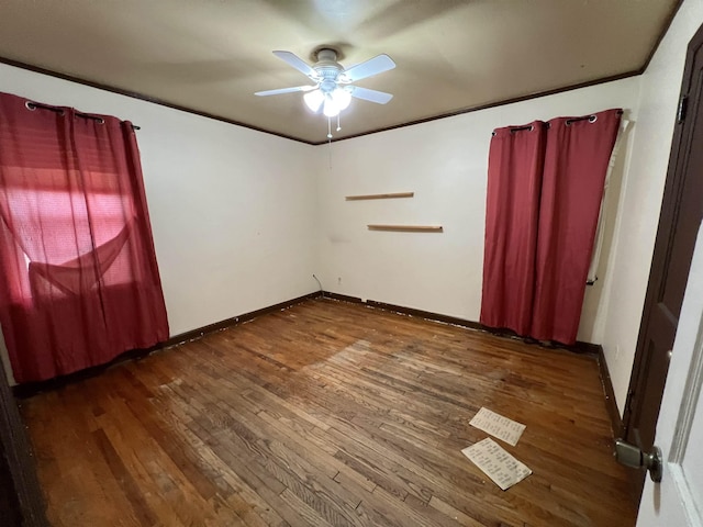 empty room with ceiling fan, dark wood-type flooring, and crown molding