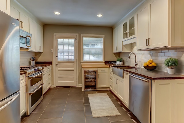 kitchen featuring white cabinets, beverage cooler, stainless steel appliances, and tasteful backsplash