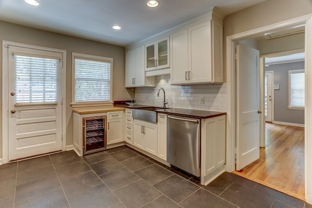 kitchen with beverage cooler, dishwasher, white cabinetry, sink, and backsplash