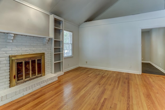 unfurnished living room with built in shelves, light hardwood / wood-style flooring, lofted ceiling, and a fireplace