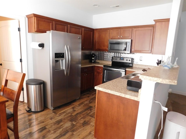 kitchen with visible vents, light countertops, appliances with stainless steel finishes, a peninsula, and dark wood-style floors