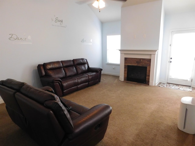 living area featuring ceiling fan, baseboards, lofted ceiling, carpet floors, and a stone fireplace