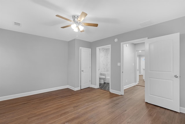 unfurnished bedroom with ceiling fan, ensuite bathroom, and hardwood / wood-style flooring