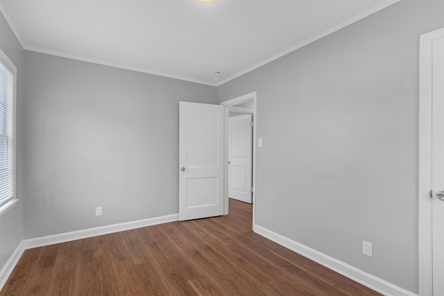 empty room with dark hardwood / wood-style flooring and crown molding