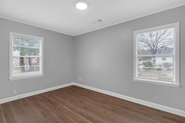 empty room featuring a wealth of natural light, dark hardwood / wood-style flooring, and ornamental molding