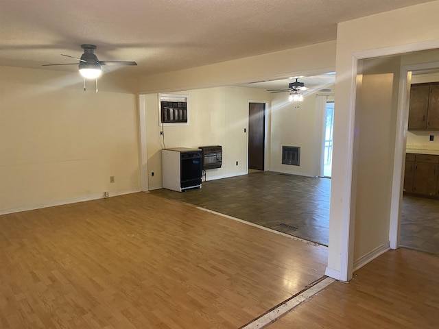 unfurnished living room with ceiling fan, heating unit, a textured ceiling, and hardwood / wood-style flooring