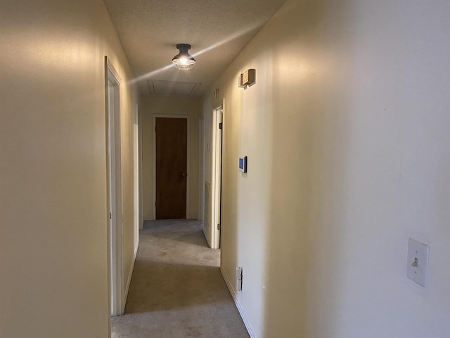 corridor with light colored carpet and a textured ceiling