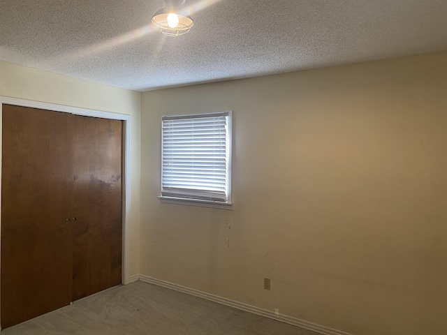 unfurnished bedroom featuring a textured ceiling, a closet, and carpet