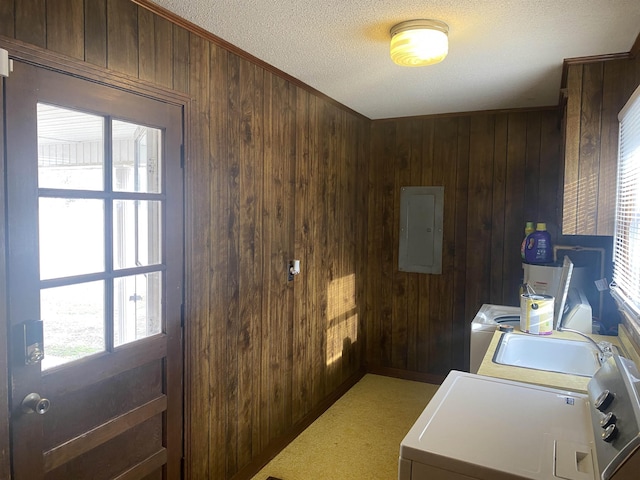 clothes washing area with washing machine and dryer, electric panel, and wood walls