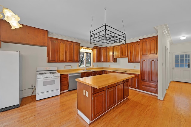 kitchen with sink, light wood-type flooring, ornamental molding, a kitchen island, and white appliances