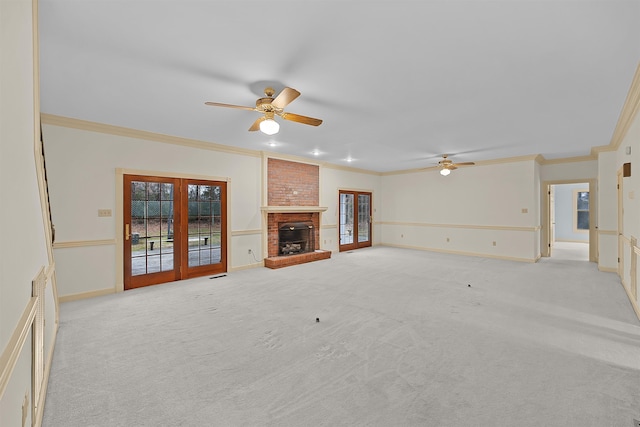 unfurnished living room featuring a fireplace, ornamental molding, ceiling fan, light carpet, and french doors