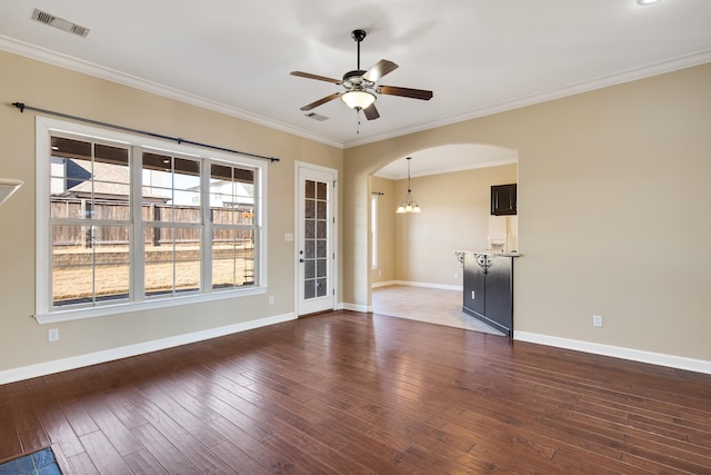 spare room featuring arched walkways, crown molding, visible vents, dark wood-type flooring, and ceiling fan with notable chandelier