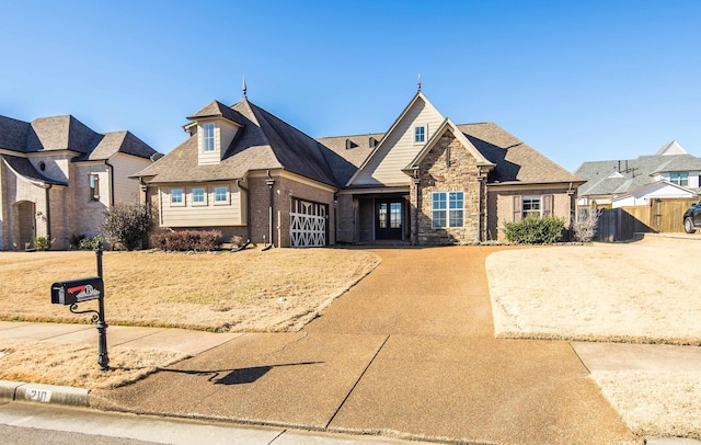 view of front of house with brick siding, a shingled roof, fence, a garage, and driveway