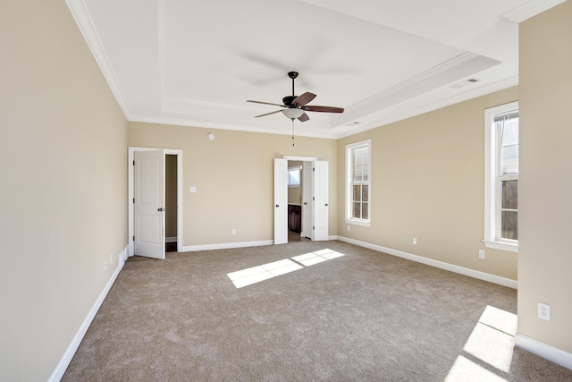 unfurnished bedroom featuring a raised ceiling, ceiling fan, light carpet, and crown molding