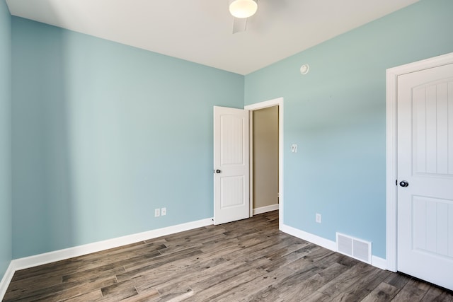 spare room with a ceiling fan, wood finished floors, visible vents, and baseboards