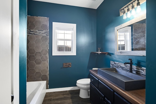 bathroom featuring toilet, vanity, wood-type flooring, and a wealth of natural light