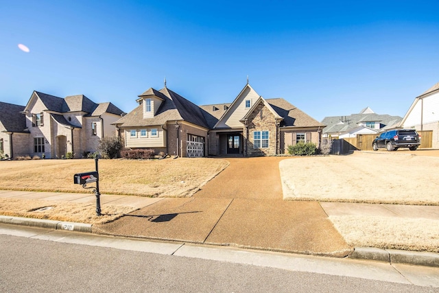 view of front facade with a garage, concrete driveway, stone siding, a residential view, and brick siding