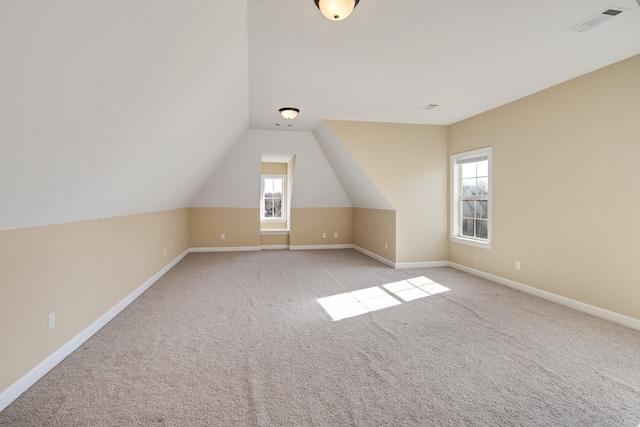 bonus room with light carpet, lofted ceiling, visible vents, and baseboards