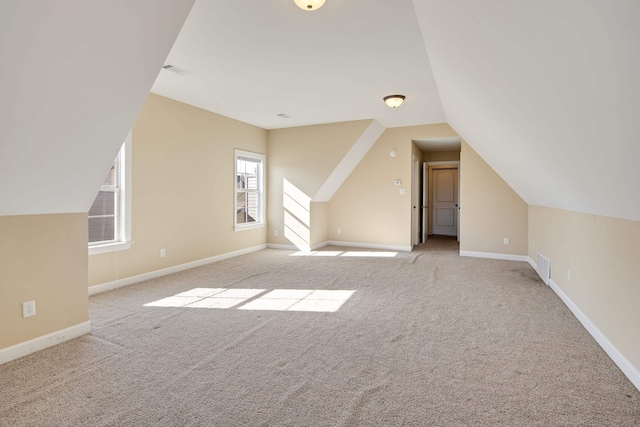 additional living space featuring lofted ceiling, baseboards, visible vents, and light colored carpet