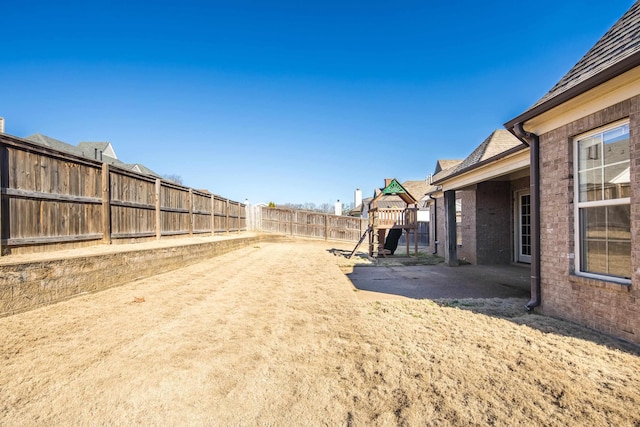 view of yard with a patio area, a playground, and a fenced backyard