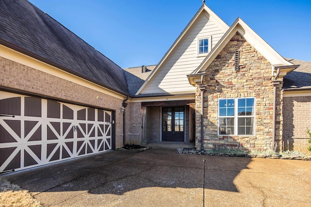 view of front of home with stone siding, an attached garage, and driveway