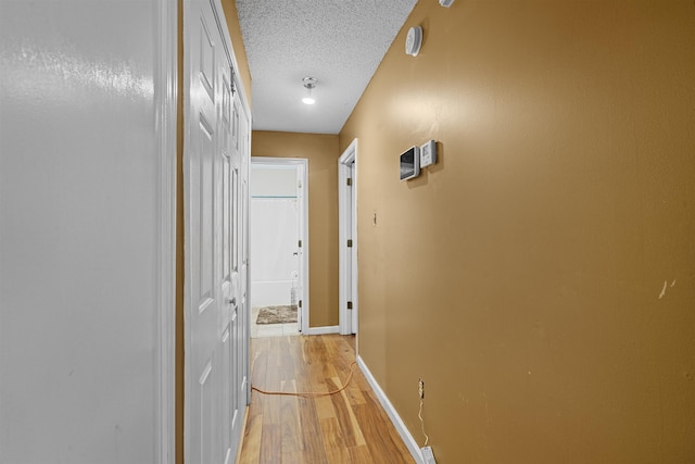 corridor featuring a textured ceiling and light hardwood / wood-style flooring