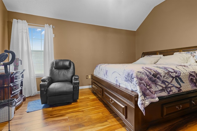 bedroom featuring lofted ceiling, light hardwood / wood-style flooring, and multiple windows