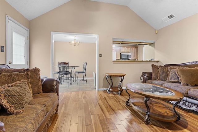 living room featuring an inviting chandelier, lofted ceiling, and light hardwood / wood-style floors