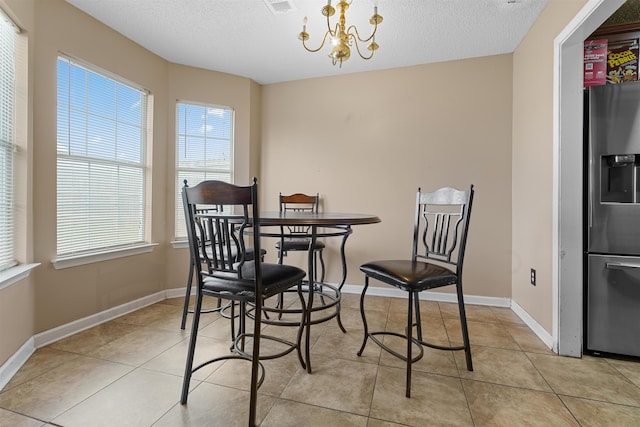 dining room featuring a textured ceiling, light tile patterned floors, and a chandelier