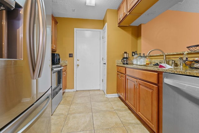 kitchen featuring light tile patterned floors, fridge, dishwasher, light stone counters, and sink