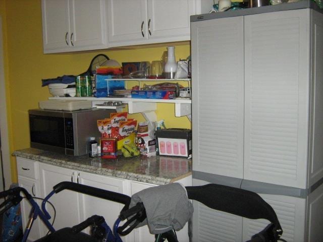 kitchen featuring light stone countertops and white cabinetry