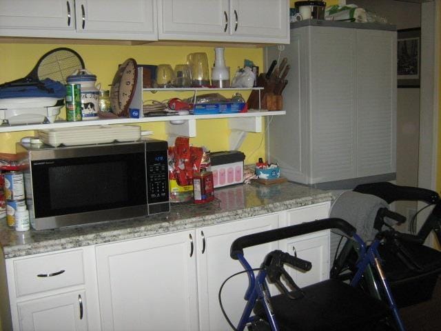 kitchen with white cabinetry and light stone counters