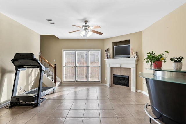 exercise room featuring ceiling fan, light tile patterned floors, and a fireplace