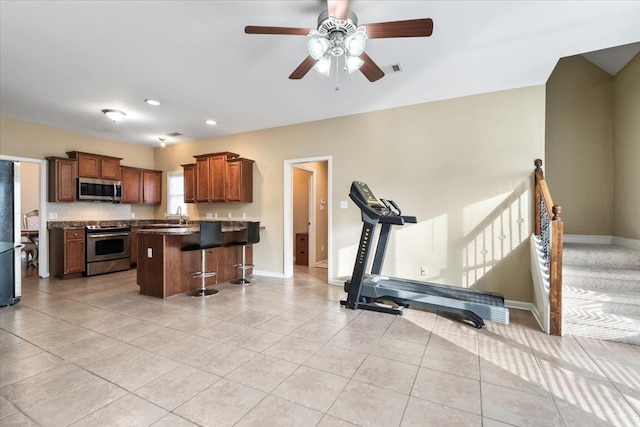 kitchen featuring light tile patterned flooring, a breakfast bar, stainless steel appliances, and a kitchen island