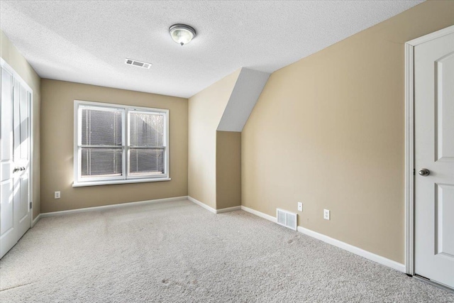 bonus room featuring a textured ceiling, light carpet, and vaulted ceiling