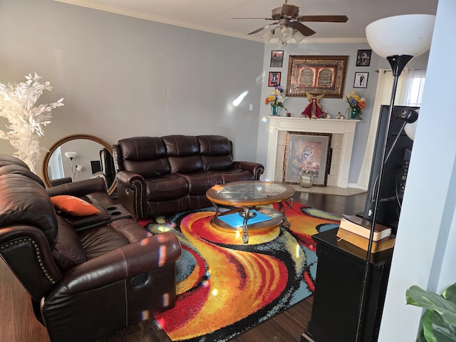 living room featuring ceiling fan, wood-type flooring, crown molding, and a tiled fireplace