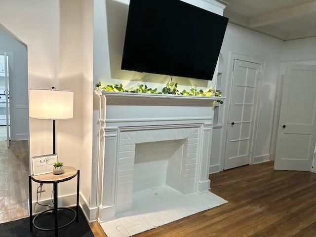 details featuring hardwood / wood-style floors, beam ceiling, and a fireplace