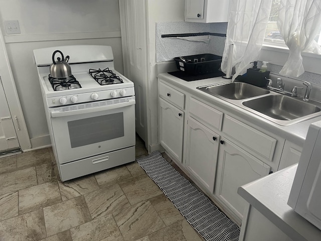 kitchen with sink, white gas range, and white cabinetry