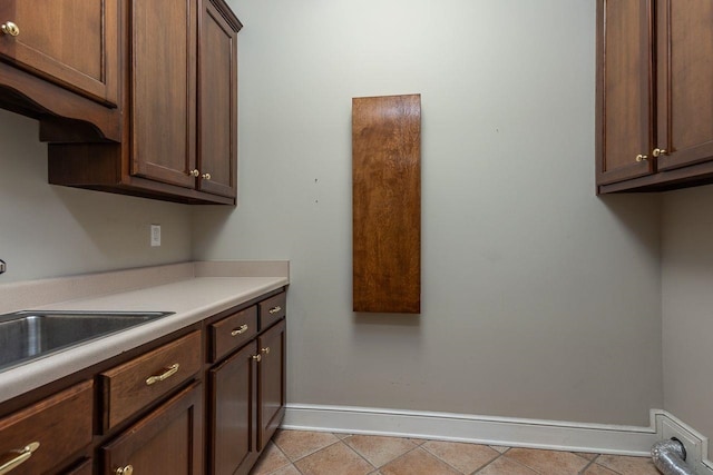 kitchen with light tile patterned floors, sink, and dark brown cabinetry