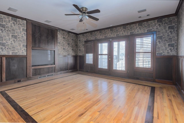 spare room with ceiling fan, wooden walls, crown molding, and hardwood / wood-style floors