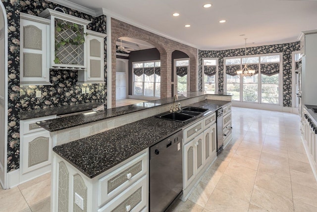 kitchen featuring dishwasher, decorative light fixtures, an inviting chandelier, an island with sink, and sink