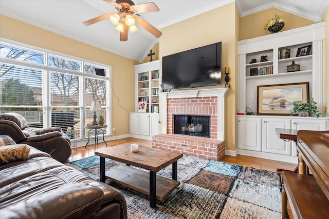 living room with lofted ceiling, ceiling fan, a fireplace, wood-type flooring, and ornamental molding