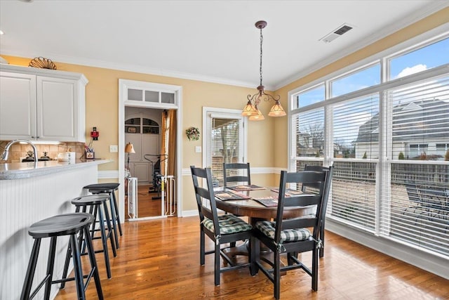 dining space featuring ornamental molding, a healthy amount of sunlight, and hardwood / wood-style flooring