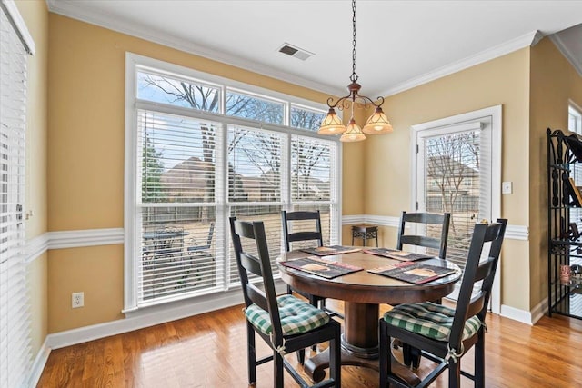 dining space featuring an inviting chandelier, ornamental molding, and a healthy amount of sunlight