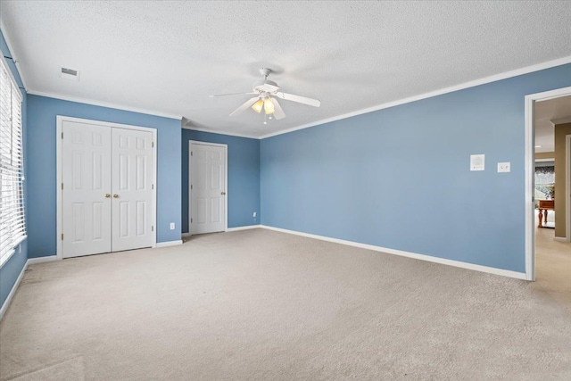 unfurnished bedroom featuring ceiling fan, crown molding, light carpet, and a textured ceiling