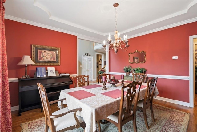 dining space with ornamental molding, hardwood / wood-style floors, and a notable chandelier