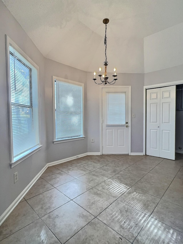 unfurnished dining area featuring vaulted ceiling, tile patterned floors, an inviting chandelier, and a textured ceiling